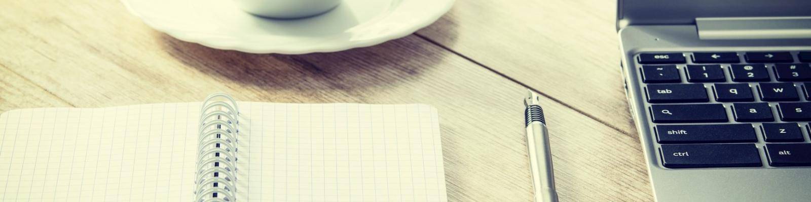 Tafel met notitieblok pen en laptop